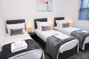 ein Zimmer mit 3 Betten und Handtüchern darauf in der Unterkunft 8 Beds Work & Family Stay Free Parking! in Southampton
