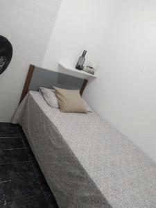 a bed in a room with a white wall at Hostel da Maisa Quarto casal com ar condicionado e banheiro compartilhado in Barreiras