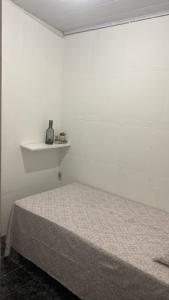 a white room with a bed and a shelf at Hostel da Maisa Quarto casal com ar condicionado e banheiro compartilhado in Barreiras