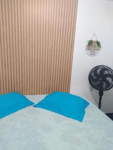 a bed with two blue pillows on top of it at Hostel da Maisa Quarto casal com ar condicionado e banheiro compartilhado in Barreiras