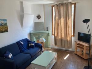 コンカルノーにあるLe Cocon de Renée, Maison atypique en ville close de Concarneauの青いソファとテレビのあるリビングルーム