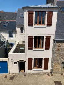 コンカルノーにあるLe Cocon de Renée, Maison atypique en ville close de Concarneauの茶色のドアと窓のある白い建物