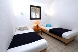 deux lits dans une petite pièce avec une fenêtre dans l'établissement Village Vacances de Ramatuelle - Le Sentier des Pins, à Saint-Tropez 31 autres photos