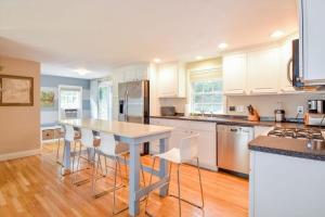 a kitchen with white cabinets and a table and chairs at Fully Renovated Walk to Scargo Lake in Dennis