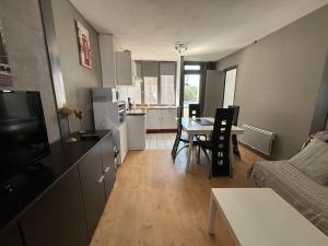 a kitchen and living room with a table and a couch at La Sarcelle in Fort-Mahon-Plage
