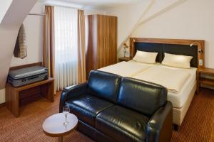 Habitación de hotel con cama y sofá de cuero en Hotel Restaurant Goldener Engel, en Heppenheim an der Bergstrasse