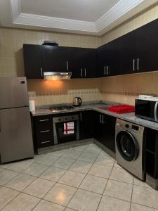 a kitchen with black cabinets and a washer and dryer at Chez Mamie Kenza in Mohammedia
