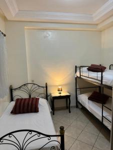 a room with two bunk beds and a table with a lamp at Chez Mamie Kenza in Mohammedia