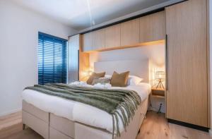una camera da letto con un letto grande con una parete in legno di Poseidon Luxe gelijkvloers appartement met tuin ,terras en gratis parking a Knokke-Heist