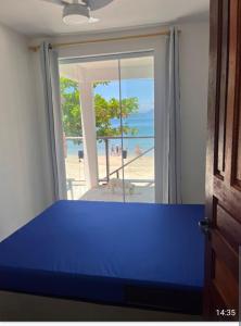a room with a blue bed and a view of the beach at Chalés Pé na Areia - Ubatuba in Ubatuba
