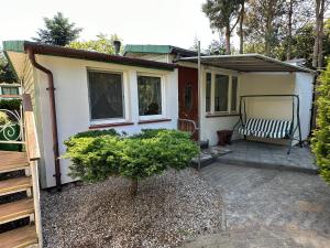 a small house with a bench on a patio at Zacisze Zygmuntowo in Zygmuntowo +47 photos