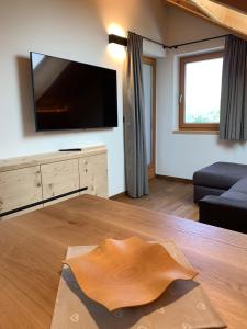 - un salon avec une grande télévision et une table en bois dans l'établissement Villa sulla passeggiata, à Ortisei