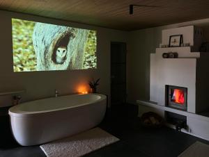 a bathroom with a bath tub and a tv on the wall at Eulenschlupf Wellnesswohnung Schwarzwald mit Sauna, Homekino & Hot Tub nahe Schweiz für Paare in Ühlingen-Birkendorf