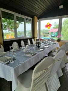 ein Esszimmer mit einem langen Tisch und weißen Stühlen in der Unterkunft Casa din povesti in Crasna din Vale