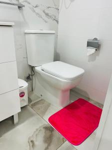 a bathroom with a white toilet and a red rug at Apartamento céntrico Vinaros 1A in Vinarós +11 photos