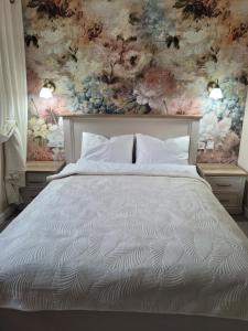 a bedroom with a white bed with a floral wallpaper at Apartament Zielona in Mysłakowice
