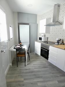 cocina con armarios blancos, mesa y fogones en Casa Monturrio, en Moguer 17 fotos más