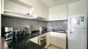 a kitchen with white cabinets and a white refrigerator at VOHE Pilar I 3 Ambientes in Villa Rosa