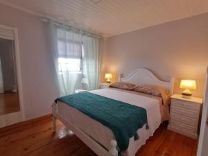 a bedroom with a white bed and a window at Casas do Baleeiro - Casa da Vinha in Cais do Pico