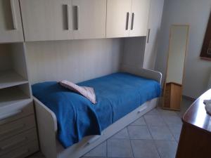 a small room with a bed with blue sheets and white cabinets at la casa di Rosa in Selvatelle