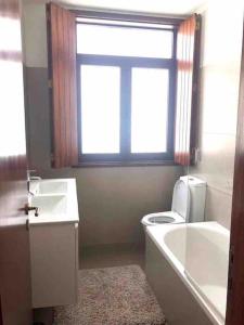 een badkamer met een bad, een toilet en een raam bij Coral Beach House in Viana do Castelo +13 foto's