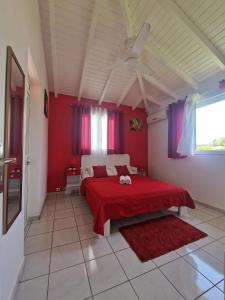 a bedroom with red walls and a bed with a red blanket at Maison charmante à Le Moule avec piscine partagée in Le Moule