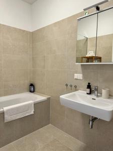 a bathroom with a tub and a sink and a mirror at City Apartment nahe Schönbrunn 13 in Vienna +9 photos