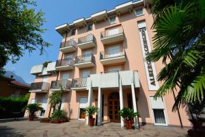 un bâtiment rose avec des palmiers devant lui dans l'établissement Hotel San Giorgio, à Arco