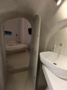 - une salle de bains blanche pourvue d'un lavabo et d'un lit dans l'établissement Basement Economy Center Rooms, à Fira