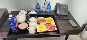 a table with a tray of breakfast food and a telephone at Adelina Hotel in Beestekraal