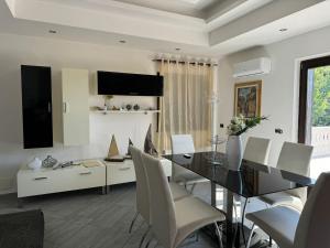 カステッランマーレ・ディ・スタービアにあるVilla Lagugaのガラスのテーブルと白い椅子のあるダイニングルーム