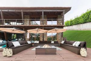 a patio with couches and umbrellas in front of a building at PONTE de LIMA CHALET POOL & GOLF in Cancinhola