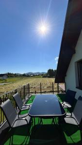 eine Terrasse mit einem Tisch, Stühlen und einem Feld in der Unterkunft Domek NA SKRAJU WSI, APARTAMENTY in Górki Wielkie