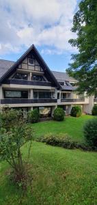 une grande maison avec une pelouse verte devant elle dans l'établissement Moderne Ferienwohnung in Hahnenklee, à Hahnenklee