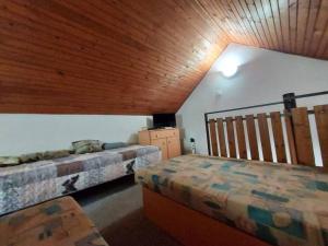 a bedroom with two beds and a wooden ceiling at Domček in Lúčky +1 photo