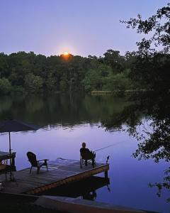 ein Mann sitzt auf einem Steg und fischt auf einem See in der Unterkunft Charming Romantic Lakefront Cottage or Guest Room Depending on Availability Near Golf in Anderson + 41 Fotos