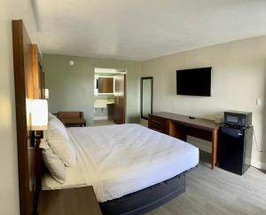 Un dormitorio con una cama, un escritorio y un televisor. en Rodeway Inn Davenport-Champions Gate, en Davenport 8 fotos más