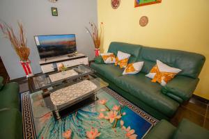 a living room with a green couch and a laptop at Immeuble rose in Douala