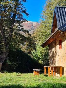 a building with a bench next to a tree at Cipresales in Villa La Angostura