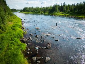 Zwei Menschen stehen auf Felsen in einem Fluss in der Unterkunft Lapin Villa Hiisi joen rannalla in Ranua