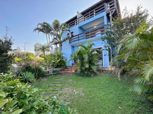 a blue house with a yard in front of it at Ampla Casa com piscina a 100m da Praia da Vila Nova - IMB001 in Imbituba