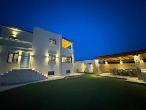 a white building with a green yard at night at Villa Thea in Egina