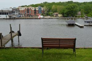 a bench sitting in the grass next to a body of water at Casual Living Extended Stay Hotels in Algonquin