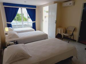 a hotel room with three beds and a window at Hotel Oasys Blue in Roldanillo