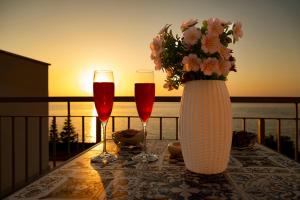a table with two glasses of wine and a vase with flowers at Exclusive B&B in Pizzo
