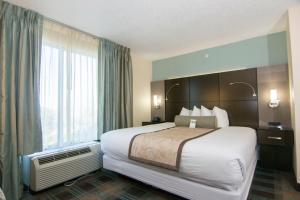 a hotel room with a large bed and a window at Wingate By Wyndham - Orlando International Airport in Orlando