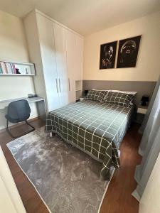a bedroom with a bed and a desk and a chair at Linda casa pertinho de Tiradentes in São João del Rei