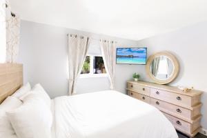 a bedroom with a white bed and a mirror at Coastal Farmhouse with mini Golf, Private Beach &Spa in Naples