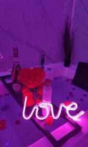 a purple room with flowers and a sign that says love at Suite bohème in Charleroi