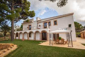 Casa blanca grande con mesa y sombrilla en Agriturismo Feudo Muxarello, en Aragona
